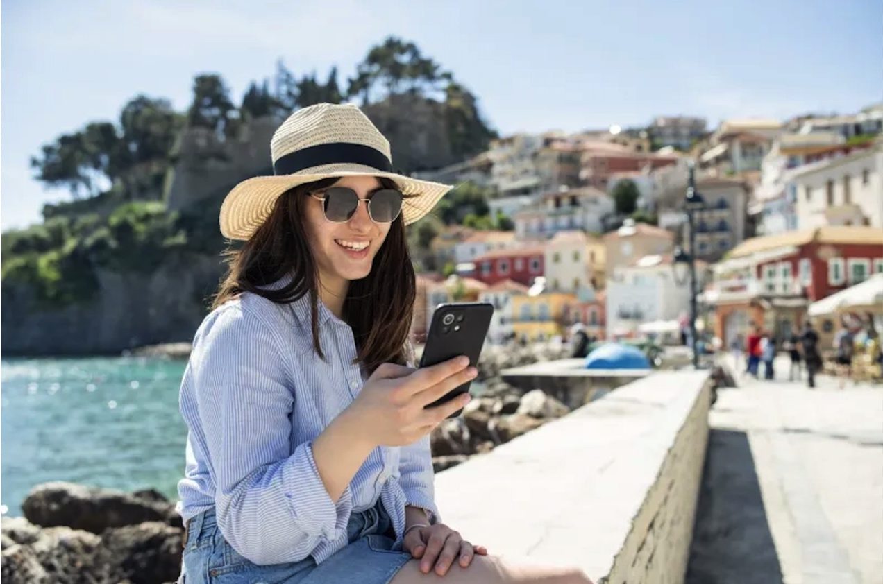 一位旅行者在阳光明媚的海滨用手机上网